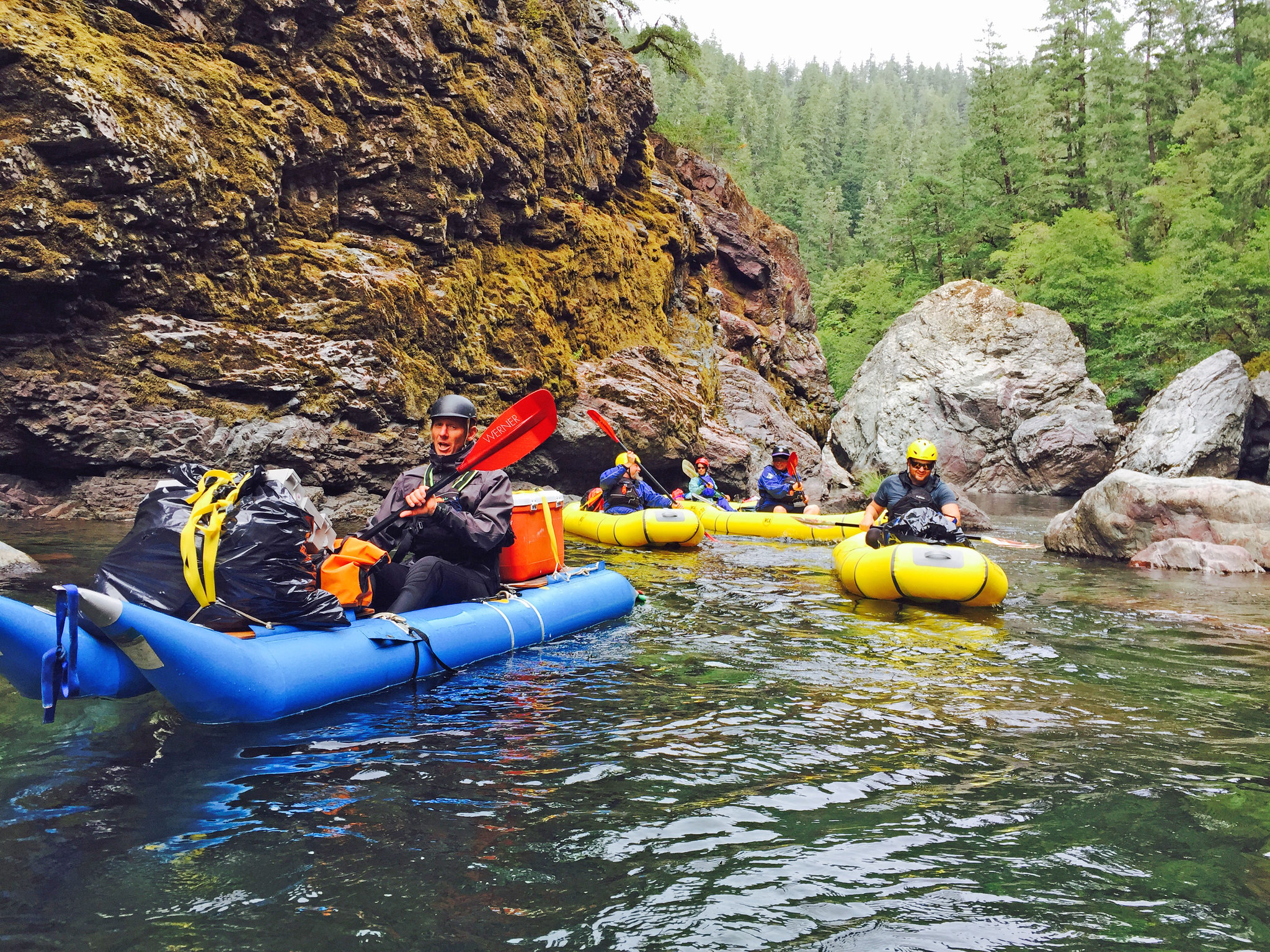 A group of kayakers paddle down a rocky river.